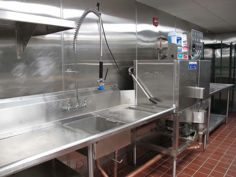 Custom stainless steel dish room tables built around a pre-rinse sink and dish machine