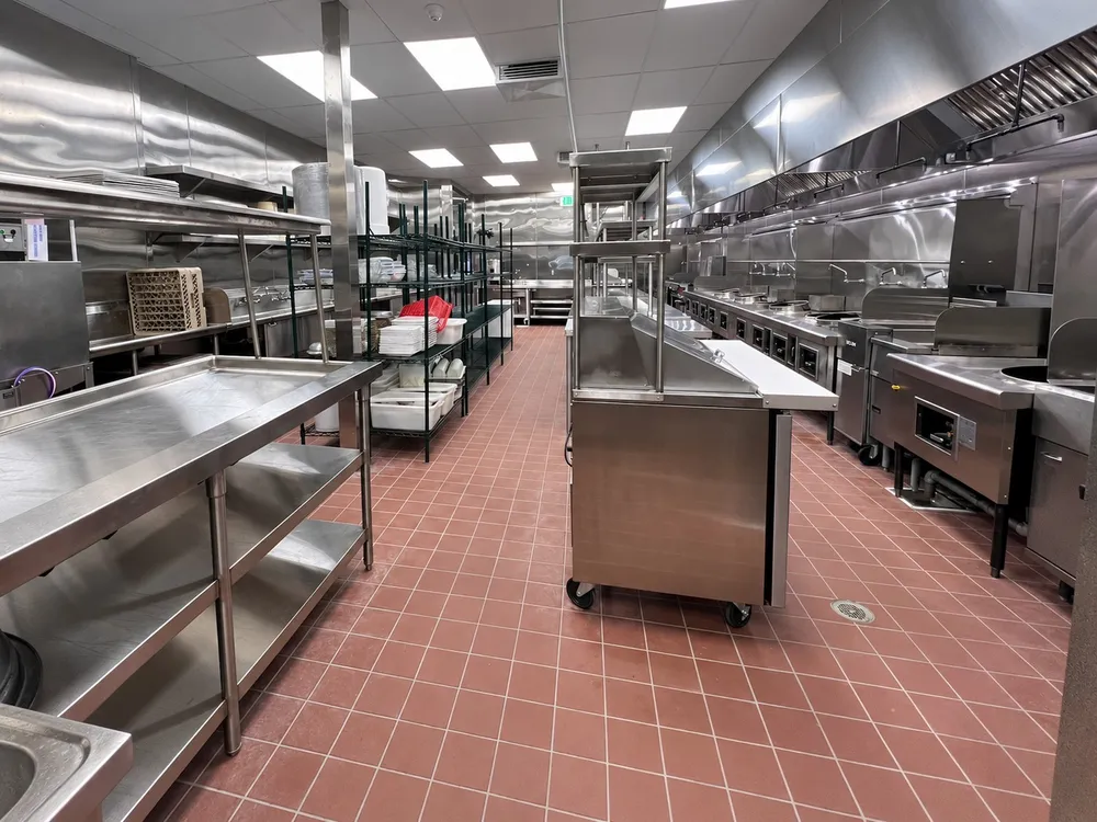 Full commercial kitchen fitted with custom stainless steel equipment, prep tables, and shelving