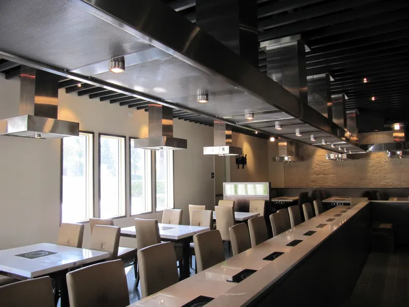 Hotpot dining room with custom stainless steel exhaust hoods over tables fitted with individual pot burners